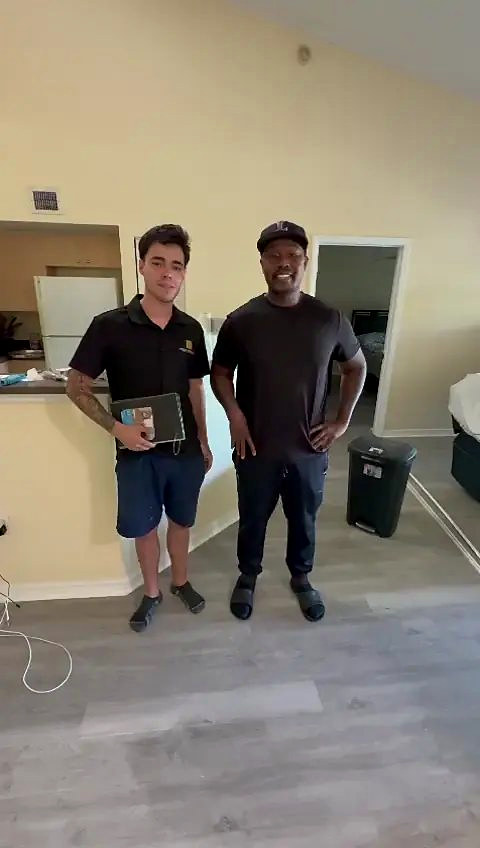 Someone from Ozzifloors, folder in hand, with a homeowner in his kitchen on the new grey plank floor
