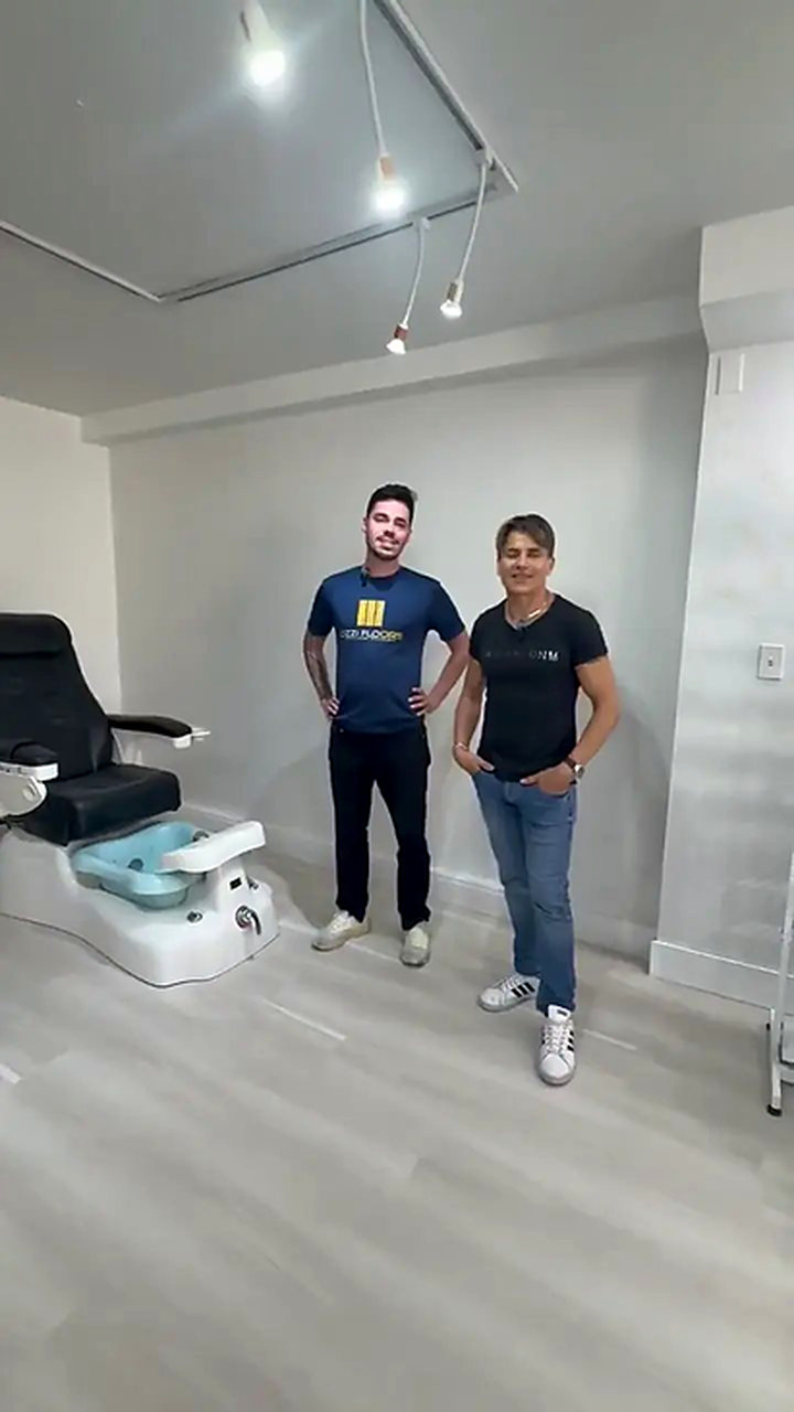 Someone from Ozzifloors with the owner of a salon, standing on the pale grey plank floor beside a pedicure chair