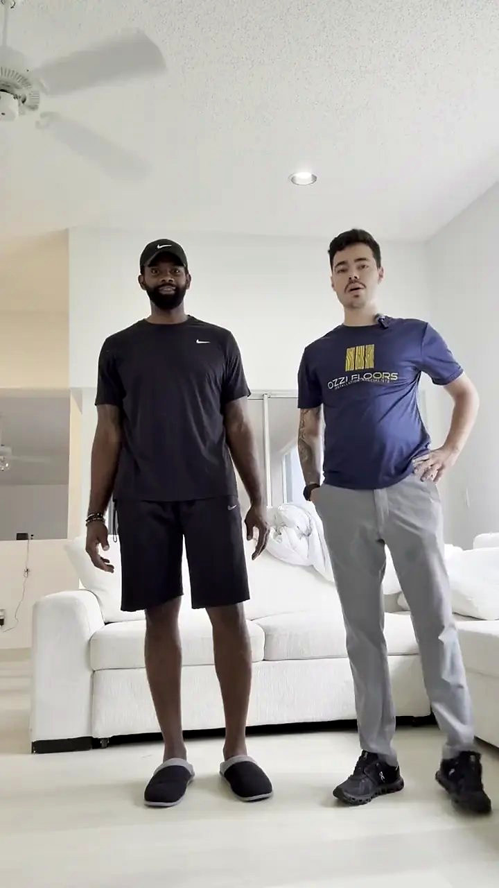 A homeowner and someone from Ozzifloors in a white living room, standing on the finished floor