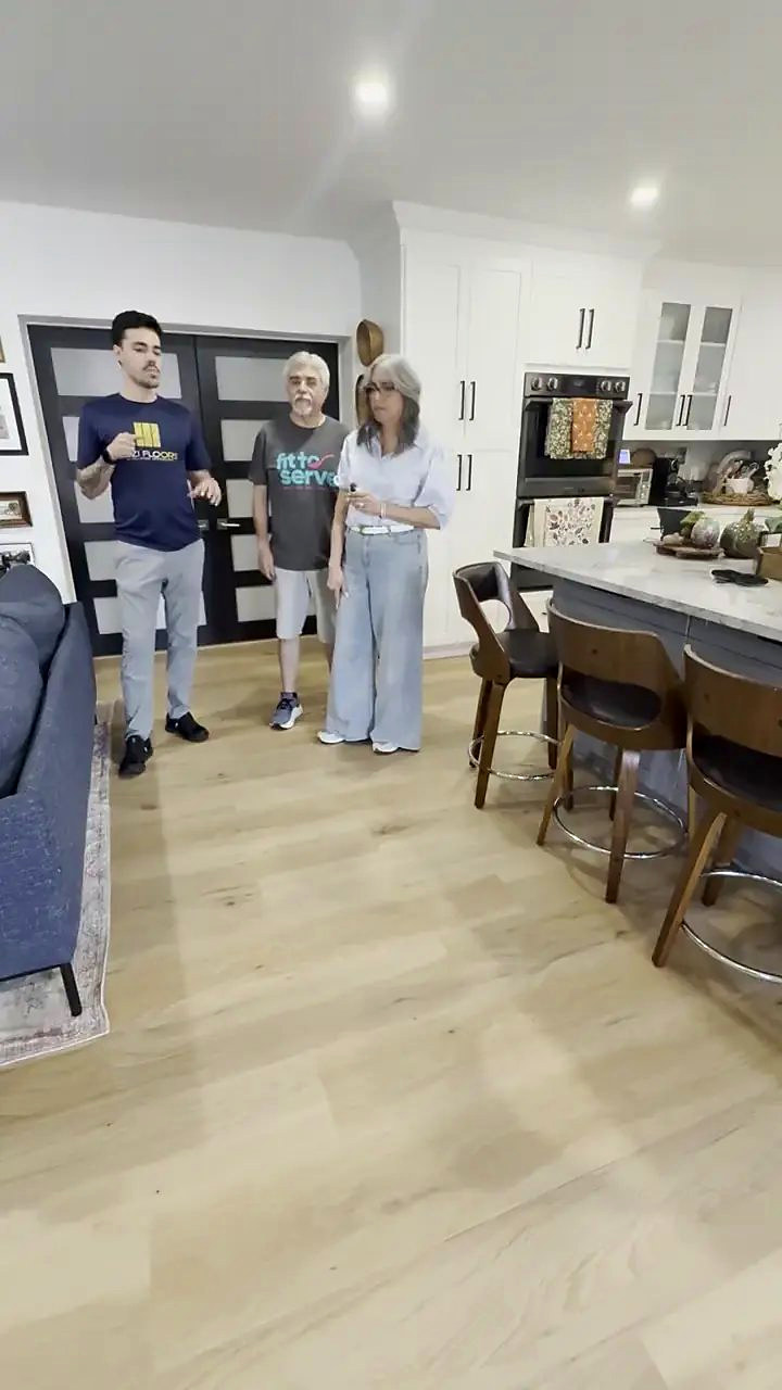 Two homeowners with someone from Ozzifloors in their open kitchen, on the new wide oak plank floor