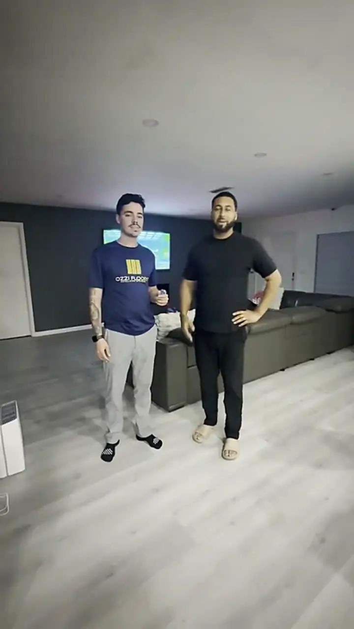 Someone from Ozzifloors with a homeowner in his dark-walled living room, on the new grey plank floor