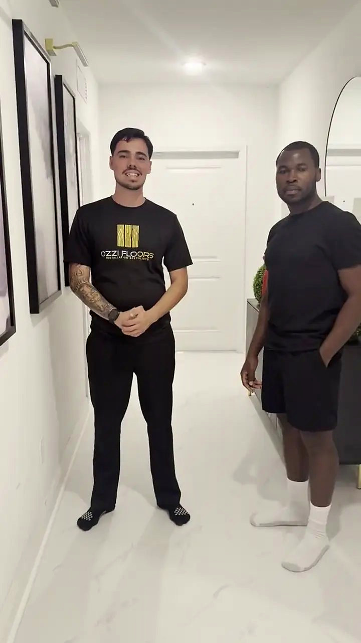 Someone from Ozzifloors with a homeowner in a white hallway, on the new large-format tile