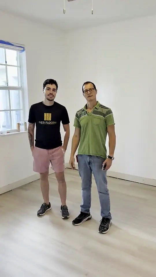 Someone from Ozzifloors and a homeowner standing on the new light oak plank floor in an empty room