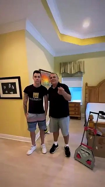 Someone from Ozzifloors with a homeowner in a yellow bedroom, the moving dolly still by the door
