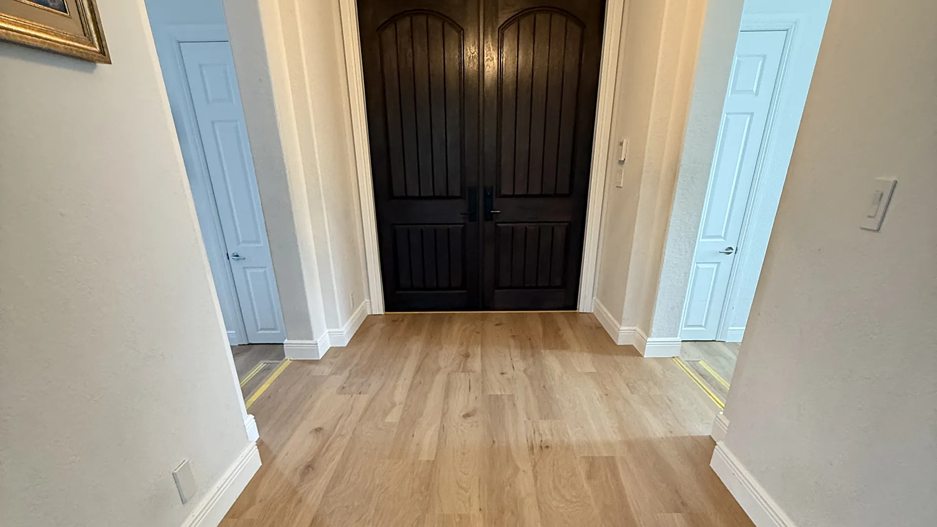 Wide oak-look plank across an entry hall to a double front door