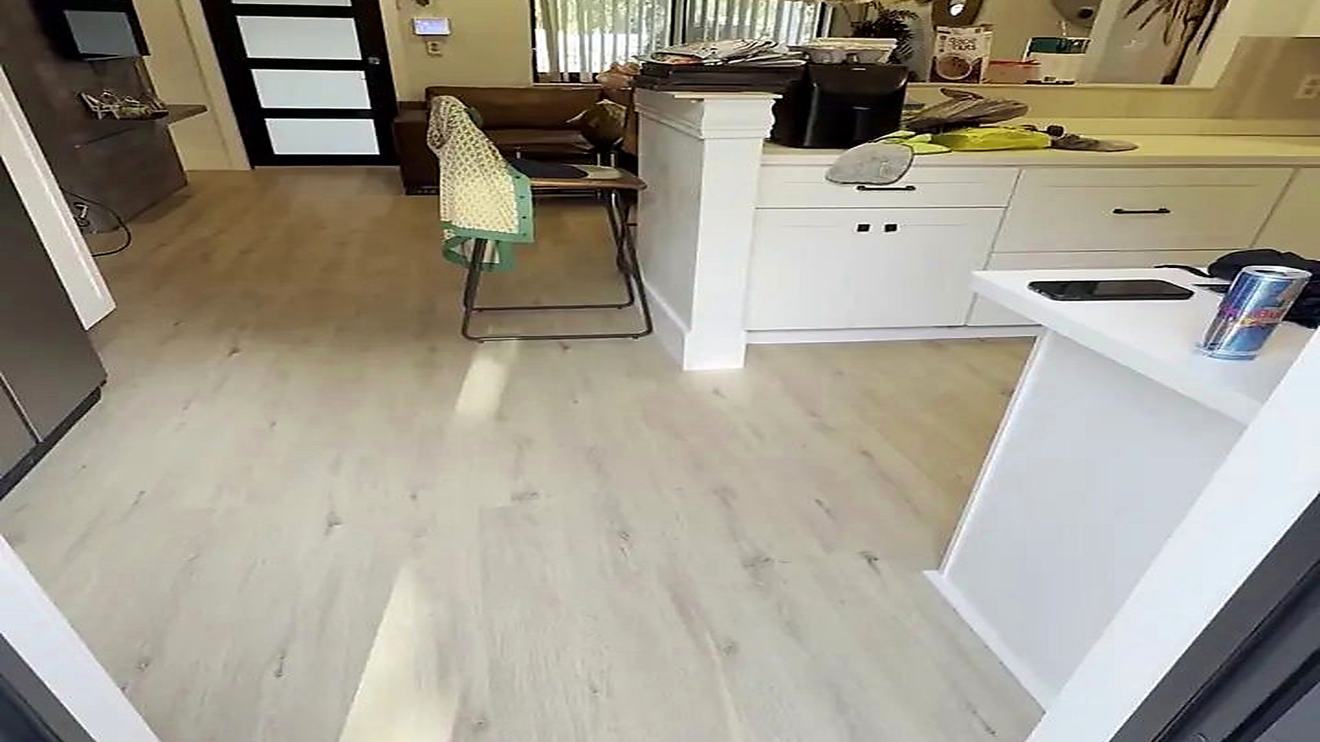 A South Florida living room with a white sectional sofa, finished in wide grey-toned plank by Ozzifloors
