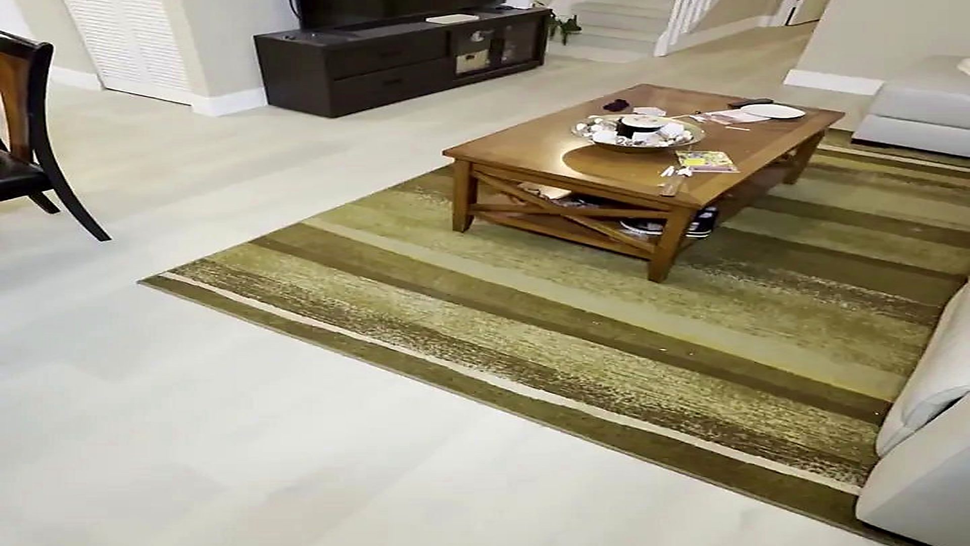Pale vinyl plank flooring in a furnished South Florida living room with a stair run behind