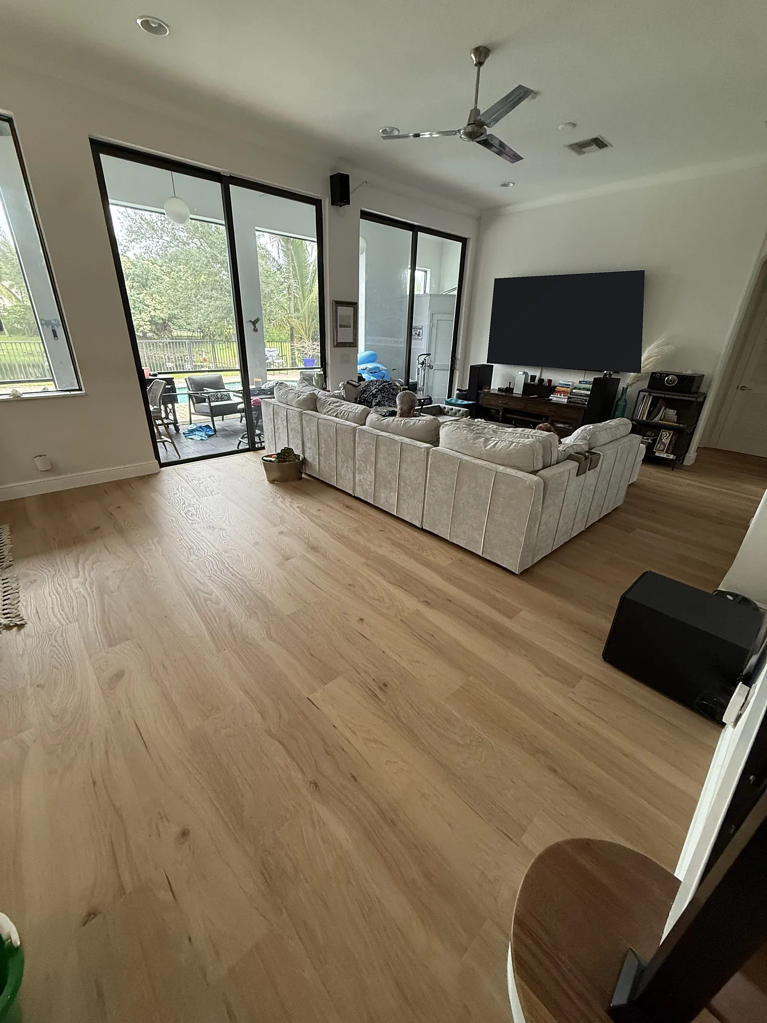 Light wide plank flooring through an open family room with sliding glass doors