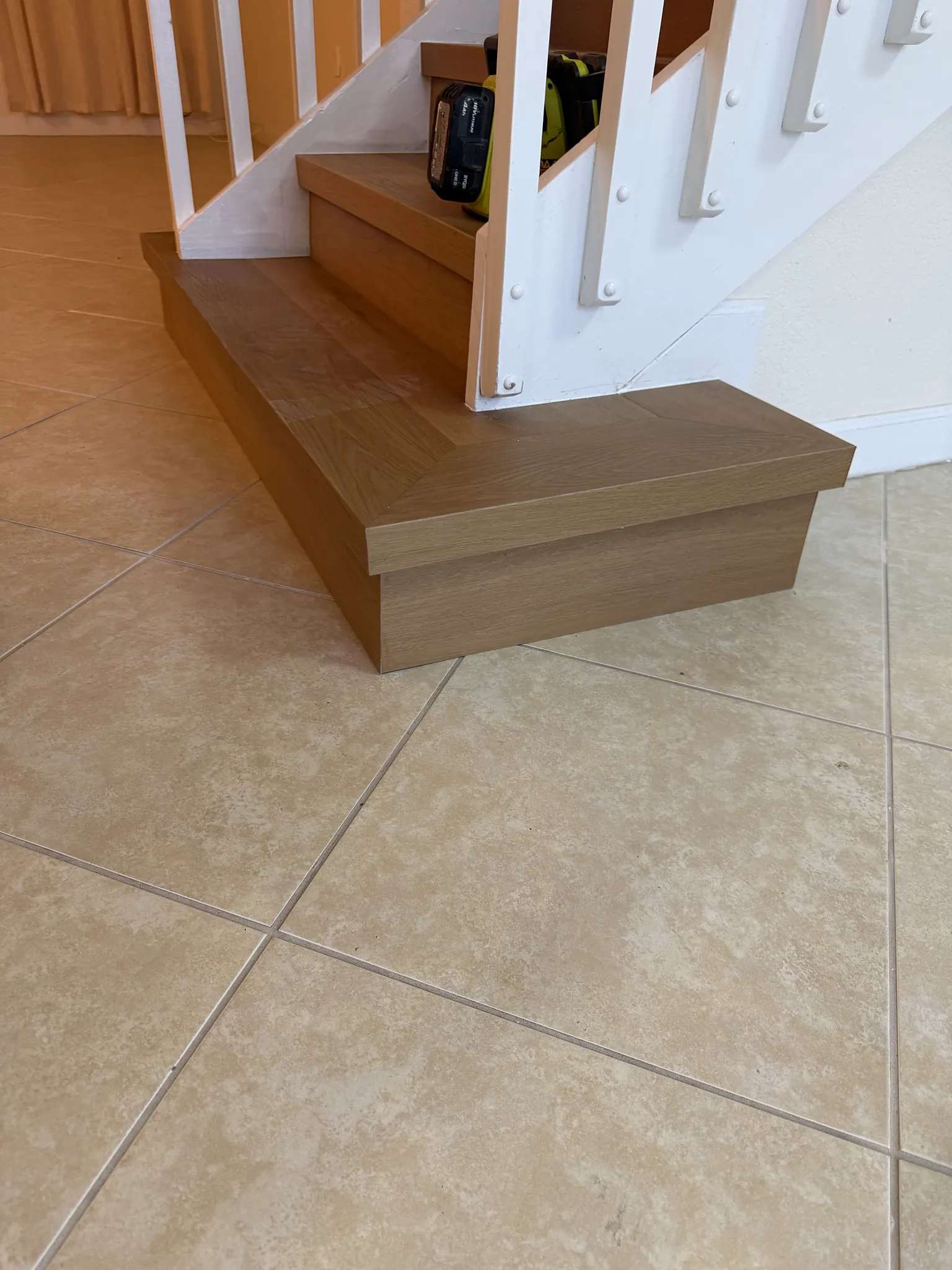 Oak-look plank stair treads with matching nosings coming down onto a cream tile floor