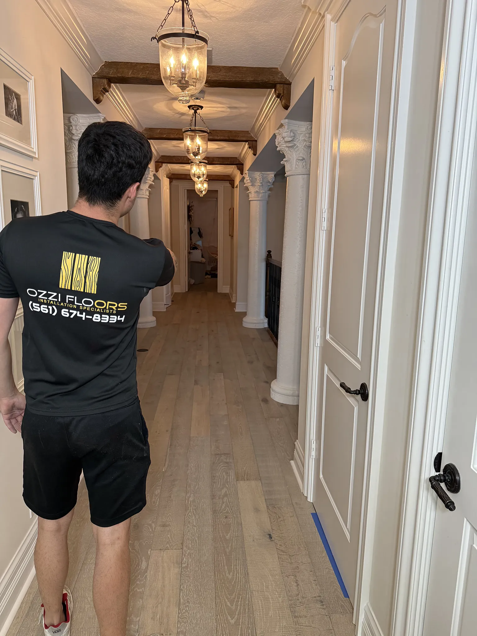 Someone from Ozzifloors in a long hallway of new oak-look plank under a row of lantern pendants