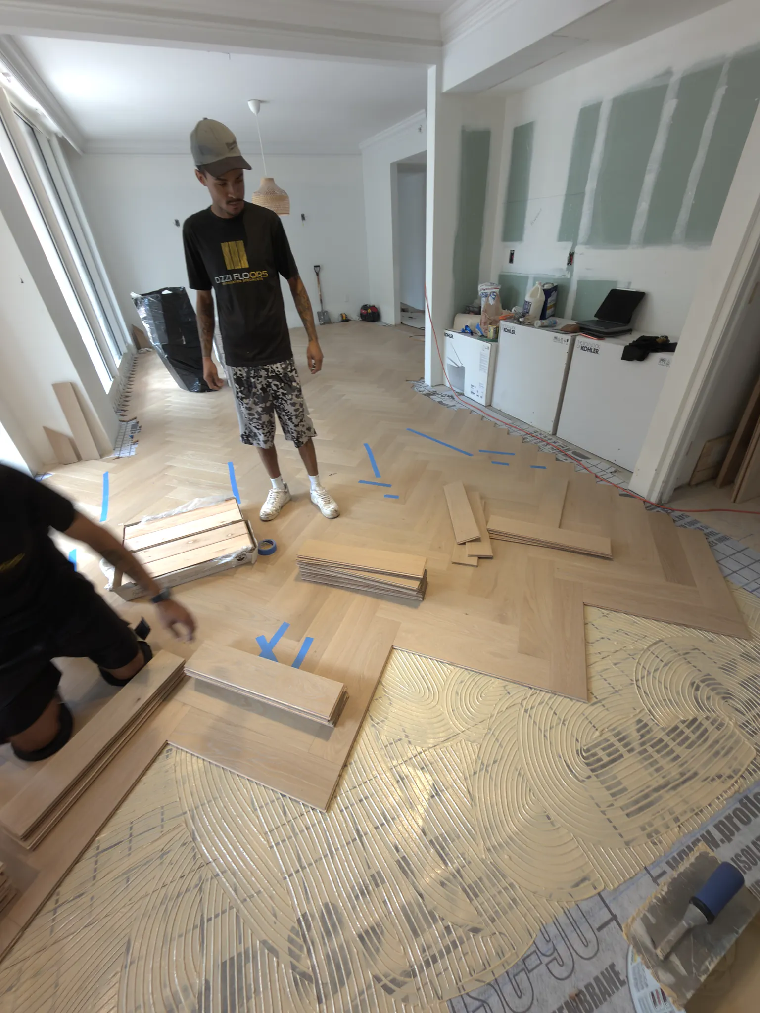 Two Ozzifloors installers laying a herringbone plank floor