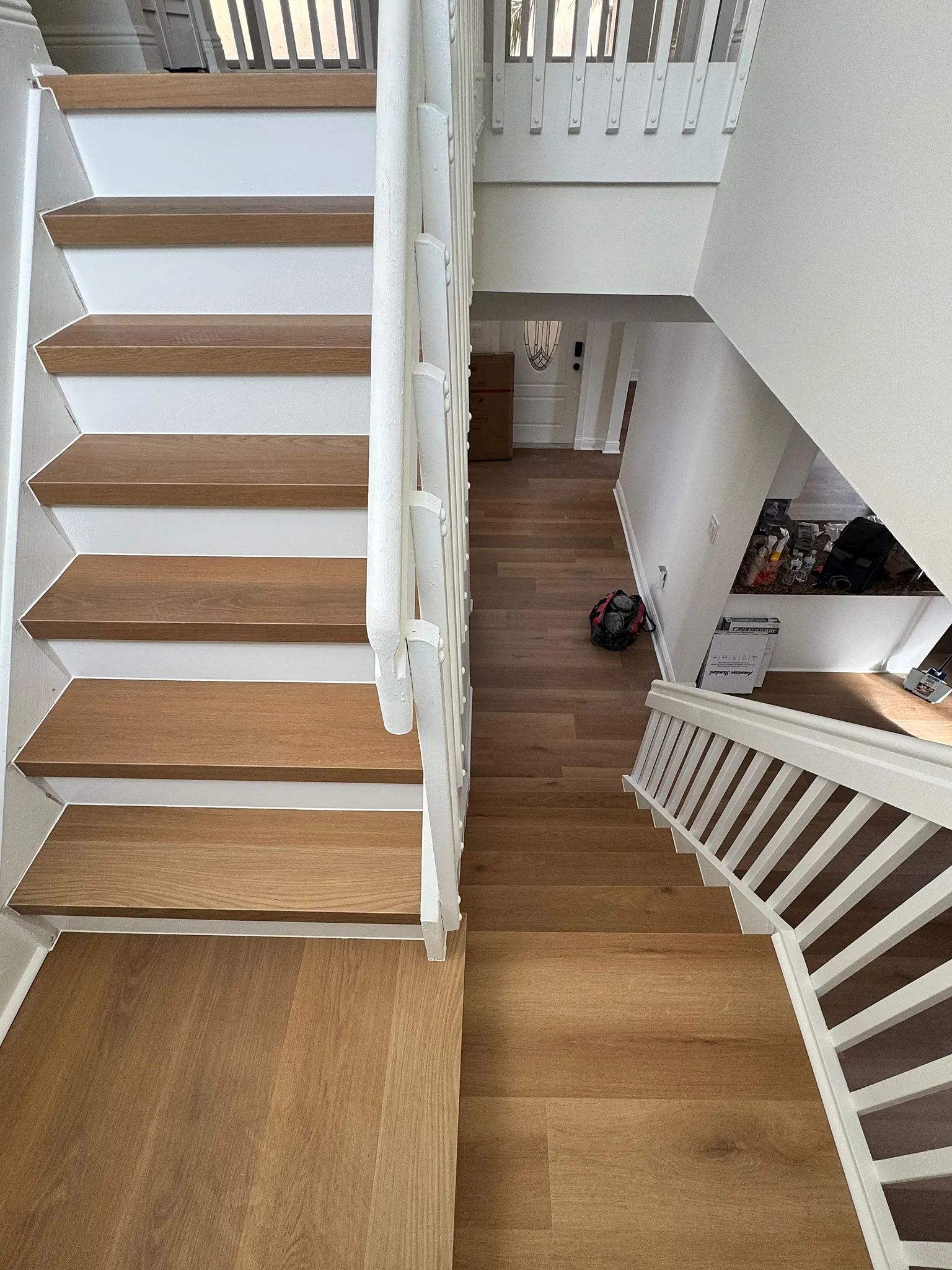 Open staircase with oak-look treads above a matching wide plank hallway
