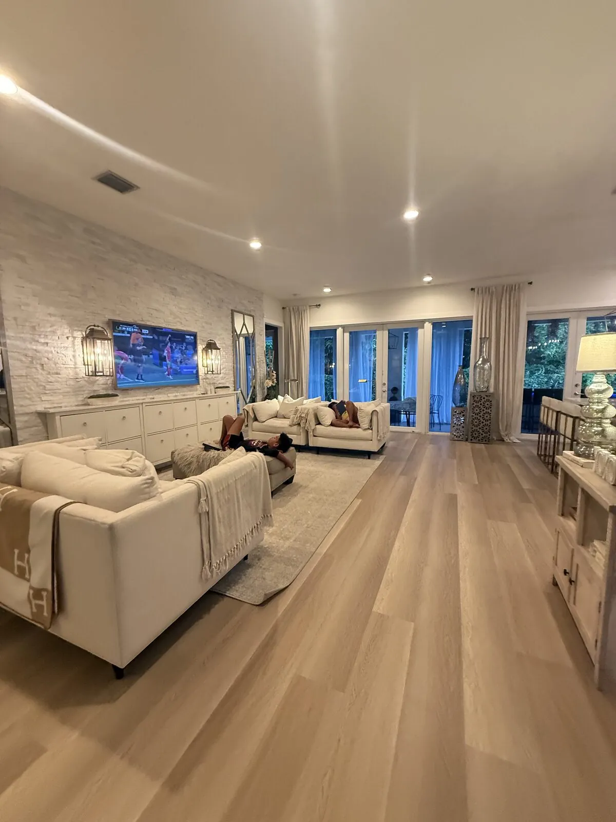 A long living room with a large area rug over light oak plank