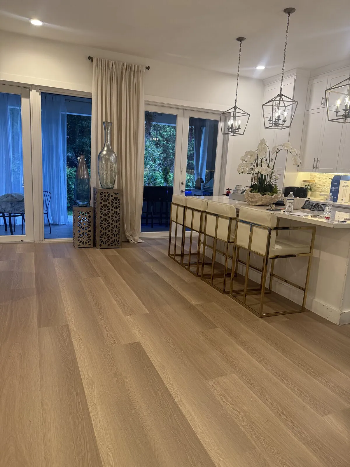 Light oak plank flooring running through a dining area in front of tall glass doors