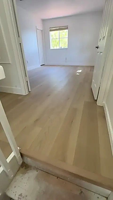 A finished room in pale oak-look vinyl plank in a Fort Lauderdale home, the slab still bare at the threshold, installed by Ozzifloors