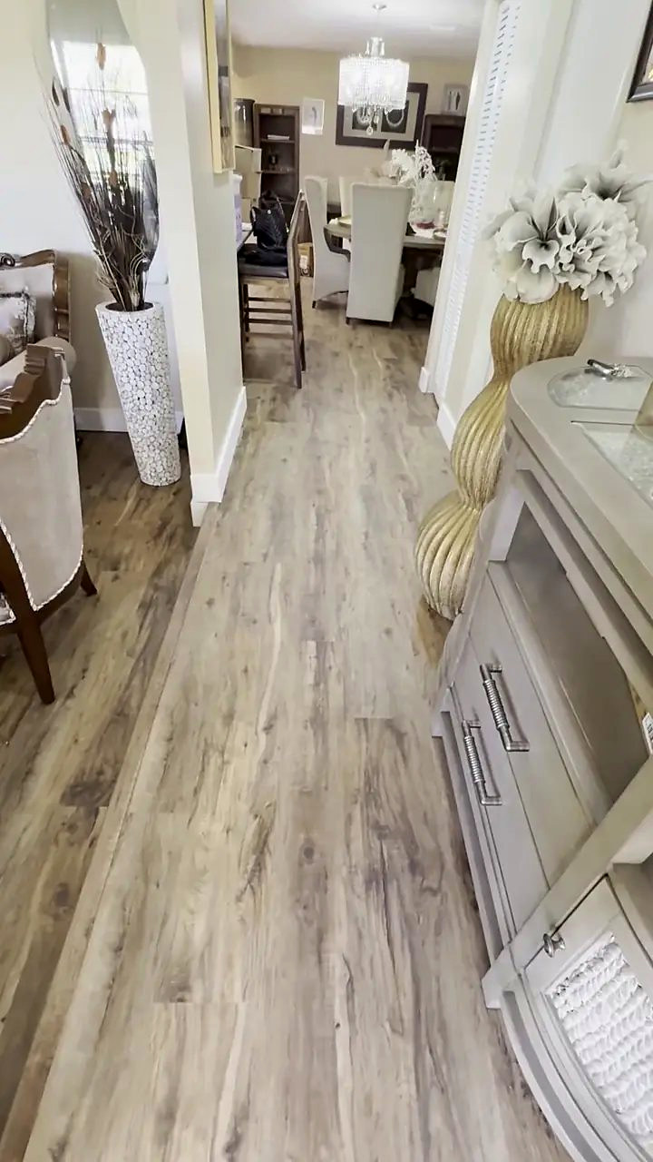 Weathered oak-look vinyl plank running from a hallway through to the dining room of a Pompano Beach home, installed by Ozzifloors